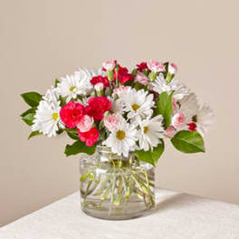 Bouquet of white daisies and pink carnations in a clear glass vase
