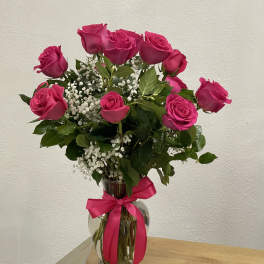 Hot pink roses in a clear glass vase with a pink ribbon