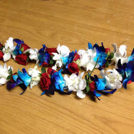 Two floral garlands with blue, white, and red flowers on a wooden surface