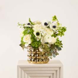 White and green floral arrangement in a gold textured vase