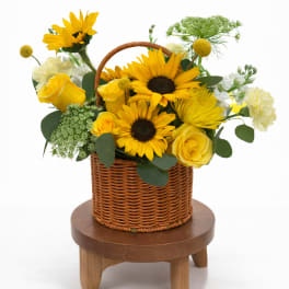 Yellow sunflowers and roses arranged in a wicker basket