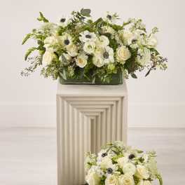 White floral arrangements with roses and anemones in glass vases