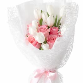 Pink roses and white tulips wrapped in white mesh with a pink ribbon