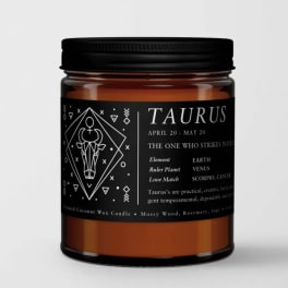 Black-labeled Taurus candle in an amber glass jar