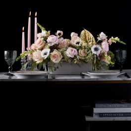 Pink floral centerpiece with candles and gold accent on a table