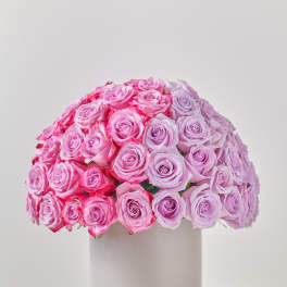 Round bouquet of pink and lavender roses in a white vase