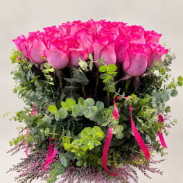 Pink roses in a white vase with eucalyptus and ribbon accents