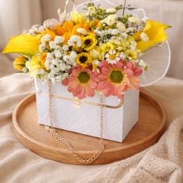 Yellow and pink mixed flower arrangement in a white gift box