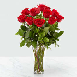 Tall bouquet of red roses in a clear glass vase