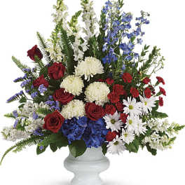 Mixed red, white, and blue floral arrangement in a white urn vase