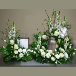 White floral funeral arrangement with a metal urn in the center