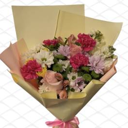 Bouquet of pink, white, and lavender flowers wrapped in gold paper with a pink ribbon