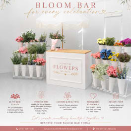Bloom bar display with assorted flowers in white buckets under a canopy