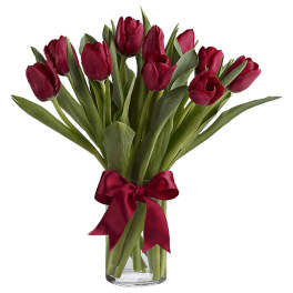 Red tulips in a clear glass vase tied with a red ribbon