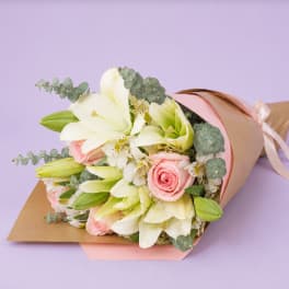 Bouquet of white lilies and pink roses wrapped in pastel paper