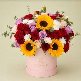 Mixed bouquet of roses and sunflowers in a pink hat box