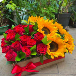Red roses and yellow sunflowers in a rectangular box with a red ribbon