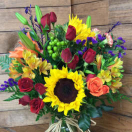 Mixed bouquet with sunflowers, roses, and lilies in a glass vase