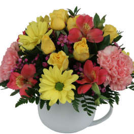 Bouquet of yellow and pink flowers in a white mug