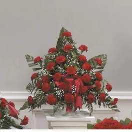 Red carnation arrangement with ribbon and greenery