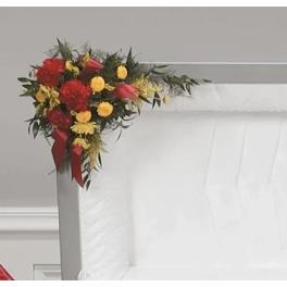 Red and yellow floral spray on a white casket