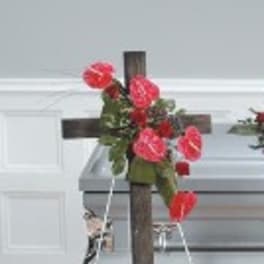 Red floral arrangement on a wooden cross