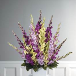 Tall purple and yellow floral arrangement in a white container