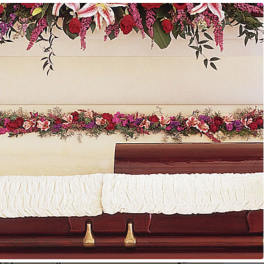 Casket with white drape and red floral sprays