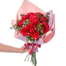 Handheld bouquet of red carnations wrapped in pink and lavender paper