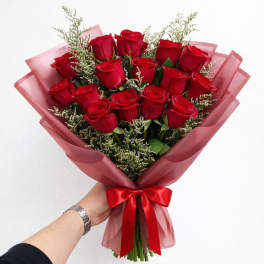 Bouquet of red roses wrapped in pink paper with a red ribbon