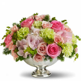 Pink and pale green floral centerpiece in a silver pedestal bowl