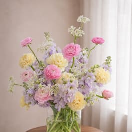 Pink and yellow flowers arranged in a clear glass vase