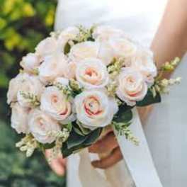 Bride holding a pale pink rose bouquet with white ribbon