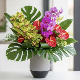 Tropical orchid arrangement in a white vase with red anthuriums
