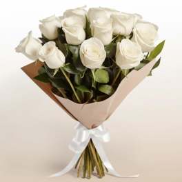 Bouquet of white roses wrapped in tan paper with a white ribbon