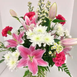 Pink lilies and white daisies in a clear glass vase