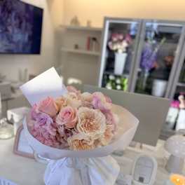 Bouquet of pink and cream roses wrapped in white paper