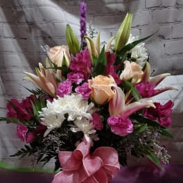Bouquet of pink and white flowers in a vase with a pink bow