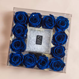 Blue roses arranged in a clear square box with a glittery center