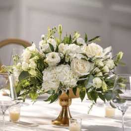 White floral centerpiece in a gold vase on a table