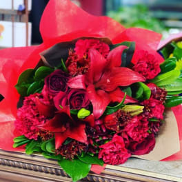 Bouquet of red lilies and dark red roses wrapped in red paper