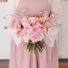 Person holding a bouquet of pink and white roses with small blue flowers