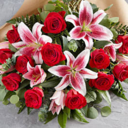 Bouquet of red roses and pink lilies wrapped in brown paper