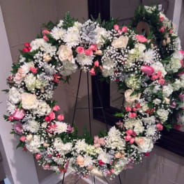 Large heart-shaped floral wreath on a stand with white and pink flowers