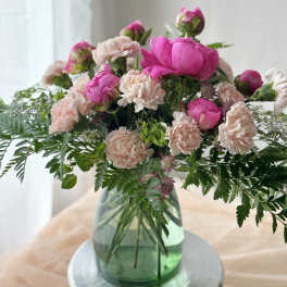 Pink peonies and pale carnations in a green glass vase