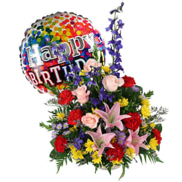 Birthday bouquet with a colorful balloon and mixed flowers in a basket