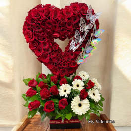 Heart-shaped red rose arrangement with white daisies and butterfly accents