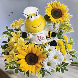 Bee plush surrounded by sunflowers and daisies