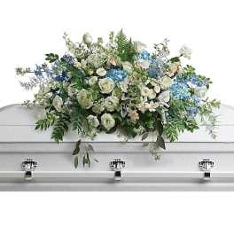 White and blue floral casket spray on a white coffin