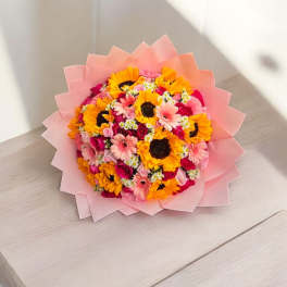 Pink-wrapped bouquet of sunflowers, gerbera daisies, and roses